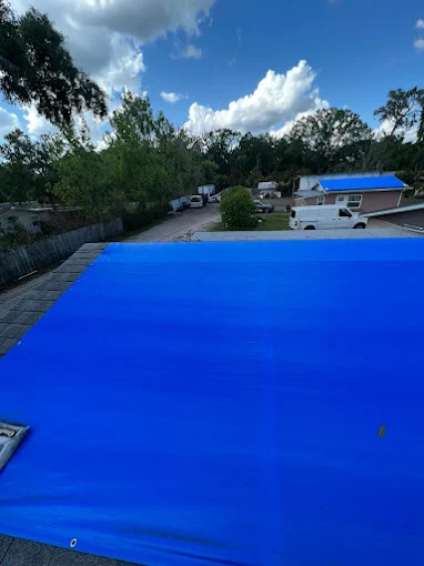 Blue emergency tarp covering a damaged roof