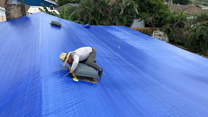 Technician securing a tarp on a roof